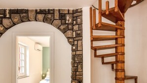 Un escalier doté d’une rampe en bois et agrémenté d’éléments en pierre, menant à une chambre à coucher avec un lit et une fenêtre.