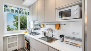 Eine moderne Küche mit integriertem Mikrowellenherd, Spüle aus Edelstahl und einem Fenster mit Blick auf Grünflächen.