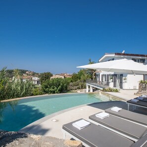 Ein moderner Poolbereich mit Liegestühlen und freiem Blick auf die umliegende Landschaft.