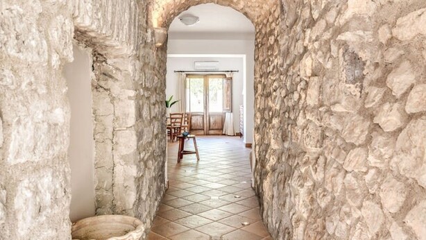 A stone archway leading to a room with a tiled floor and a large vase. - Villa Mimosa in Massa Lubrense (Massa Lubrense)