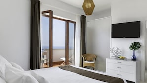 Ein modernes Hotelzimmer mit einem großen Bett, einem Flachbildfernseher, einem Schminktisch und einem Sessel am Fenster.