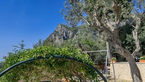 Eine Steintreppe mit einem Metallbogen, umgeben von Grün und einem Berg im Hintergrund.
