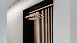 Un placard moderne avec des lambris en bois verticaux et une tringle pour suspendre les vêtements.