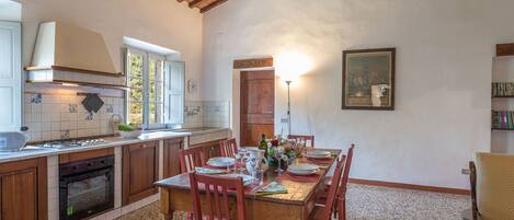 Una cocina con armarios de madera, una estufa y un comedor con una mesa preparada para cuatro.