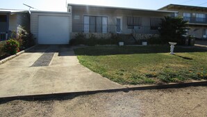 A two-story residential building with a garage, a front lawn, and a small garden area.