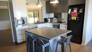 A modern kitchen with a central island, stainless steel appliances, and bar stools.