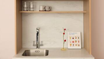 A kitchen with a stainless steel sink, wooden cabinets, and a marble backsplash.