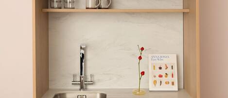 A kitchen with a stainless steel sink, wooden cabinets, and a marble backsplash.