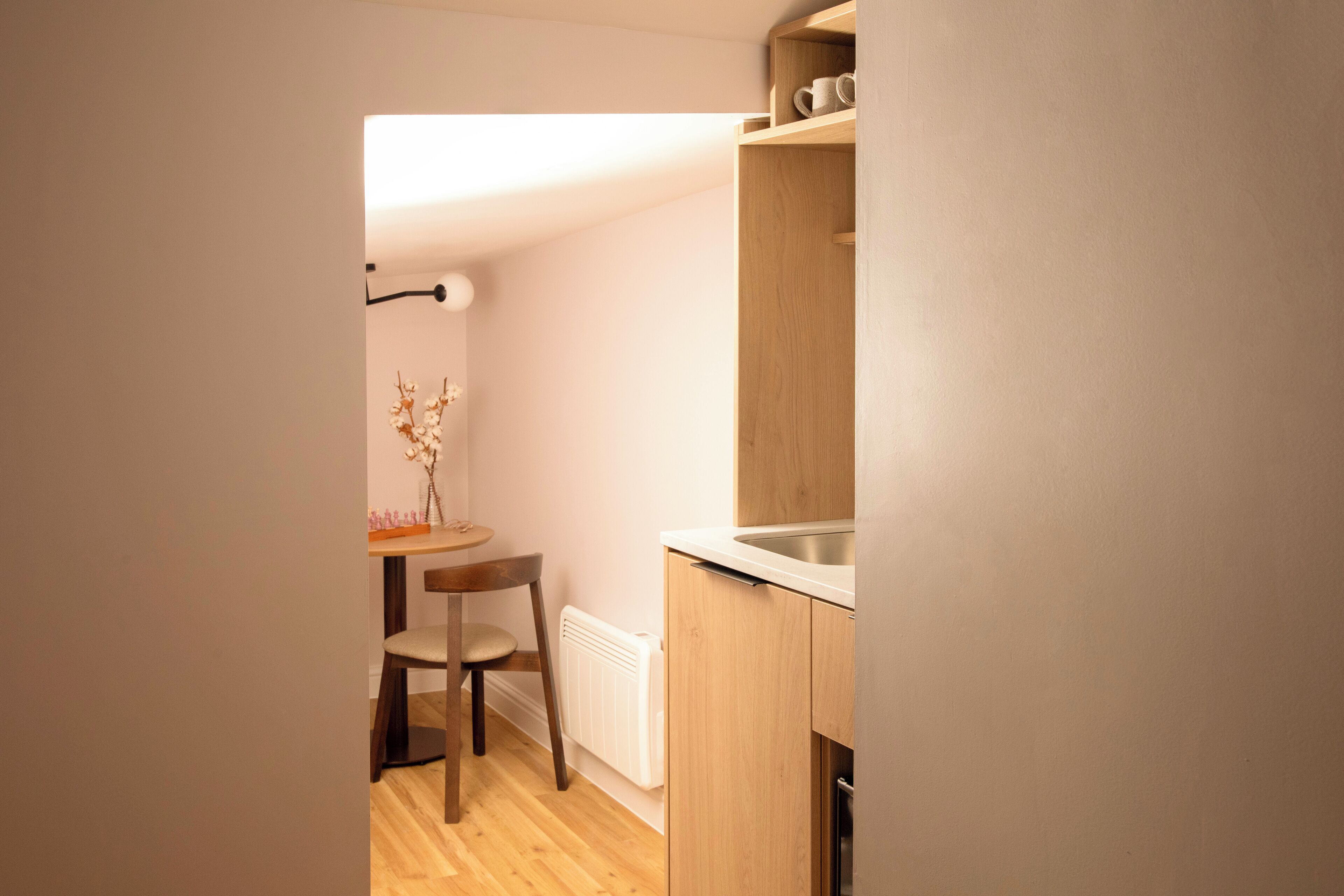 A small kitchenette with a wooden table, a chair, and a radiator.