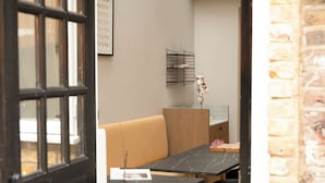 Een moderne kamer met een zwarte deur, een beige bank, een zwarte tafel met een laptop en een kleine plant.