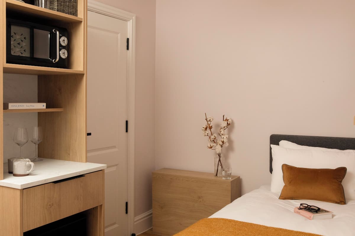 Een keurig opgemaakt slaapkamer met een bed, nachtkastje en een houten plankunit.