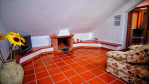 A cozy living room with a fireplace, a television, and a floral sofa. - Vacation home with dog boarding (Messina)