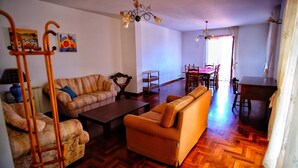 A living room with a sofa, armchair, and a dining table with chairs. - Vacation home with dog boarding (Messina)