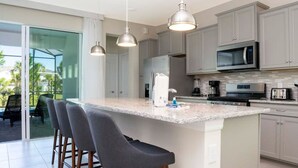 Cozinha moderna com uma ilha grande, banquetas e uma porta de correr de vidro que dá para uma área externa.