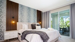 Quarto moderno com uma cama grande, mesa de cabeceira e porta de vidro deslizante para uma varanda.