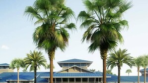 A hotel with a central entrance, palm trees, and a parking lot. - 1807 Amazing 5BR Brand New House (Davenport)