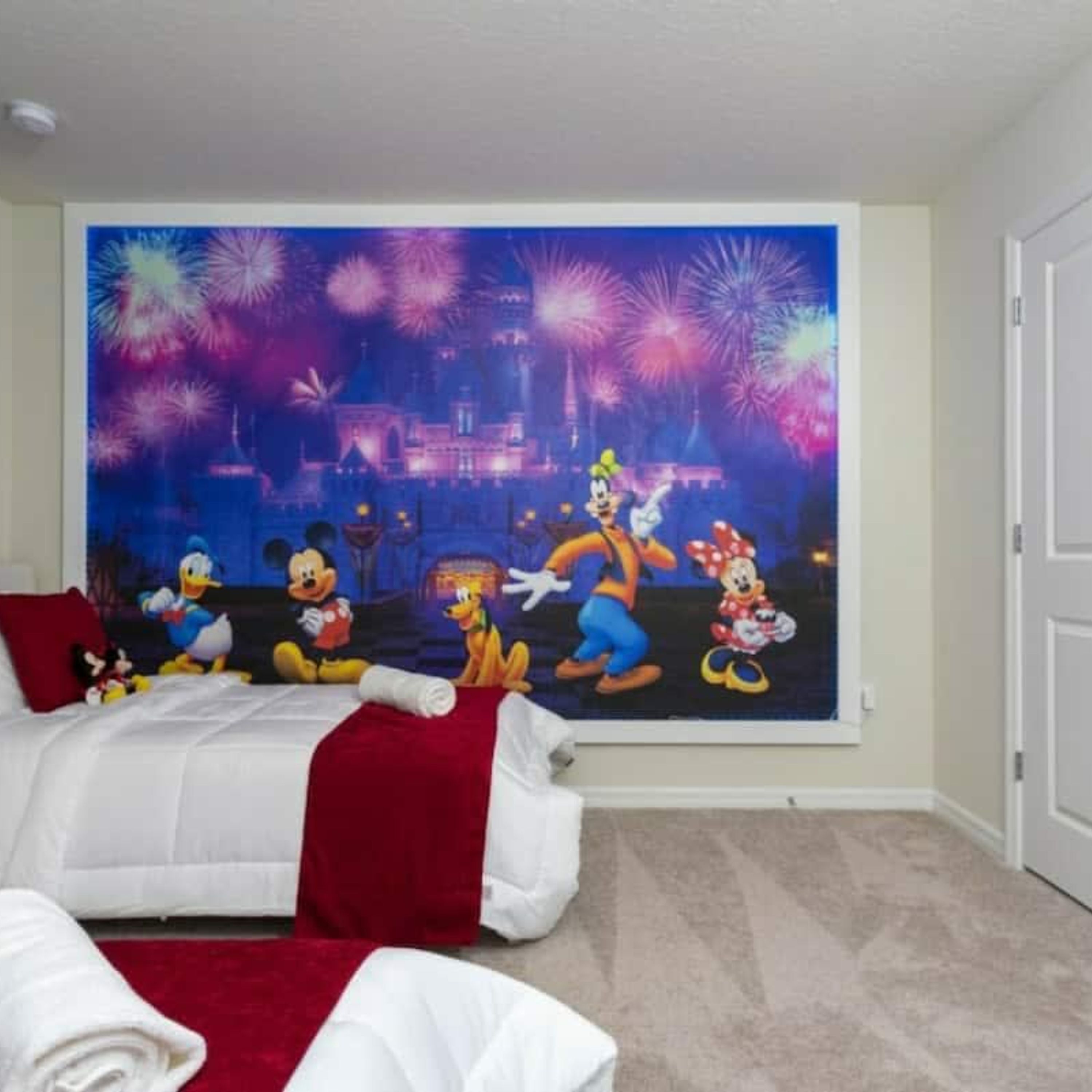 Een hotelkamer met een groot muurschildering van geanimeerde personages en vuurwerk.