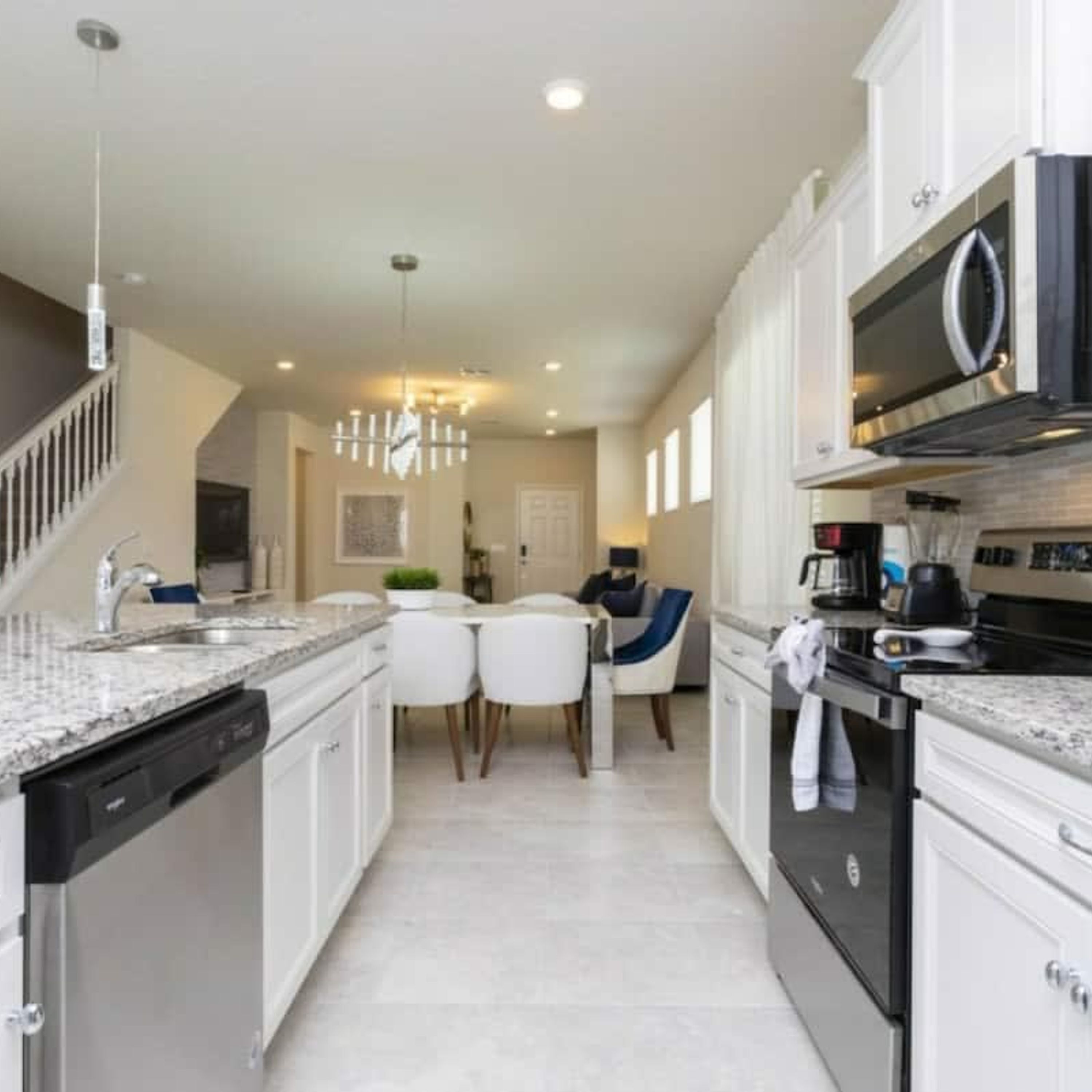 A modern kitchen with white cabinetry, a built-in dishwasher, a black stove, and a microwave.