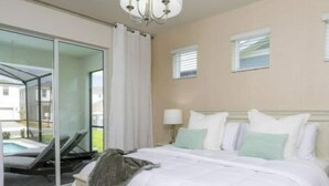A bedroom with a bed, a chandelier, a window, and a view of a pool. - 1807 Amazing 5BR Brand New House (Davenport)