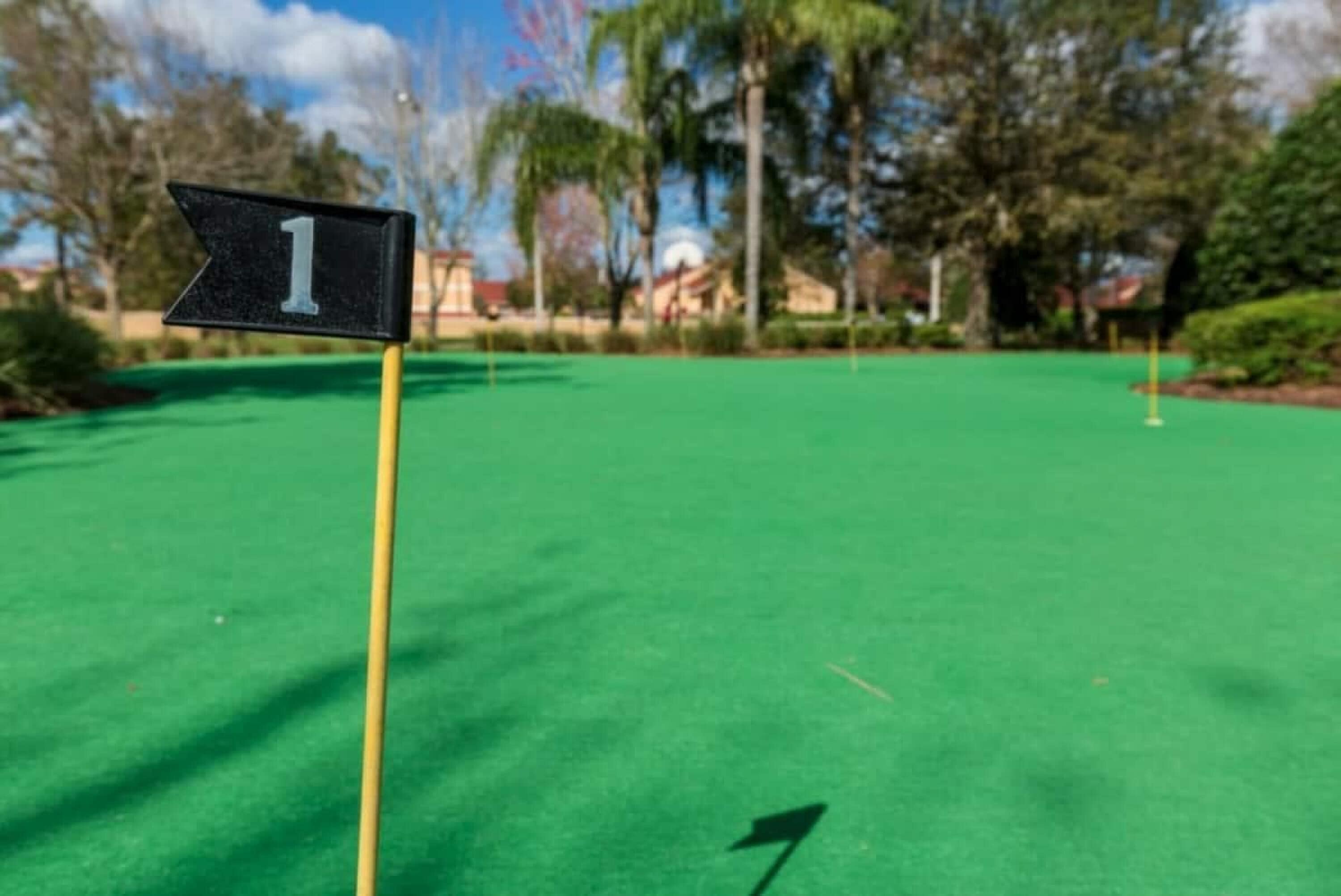 A golf course with a green flag marked '1' on a tee.
