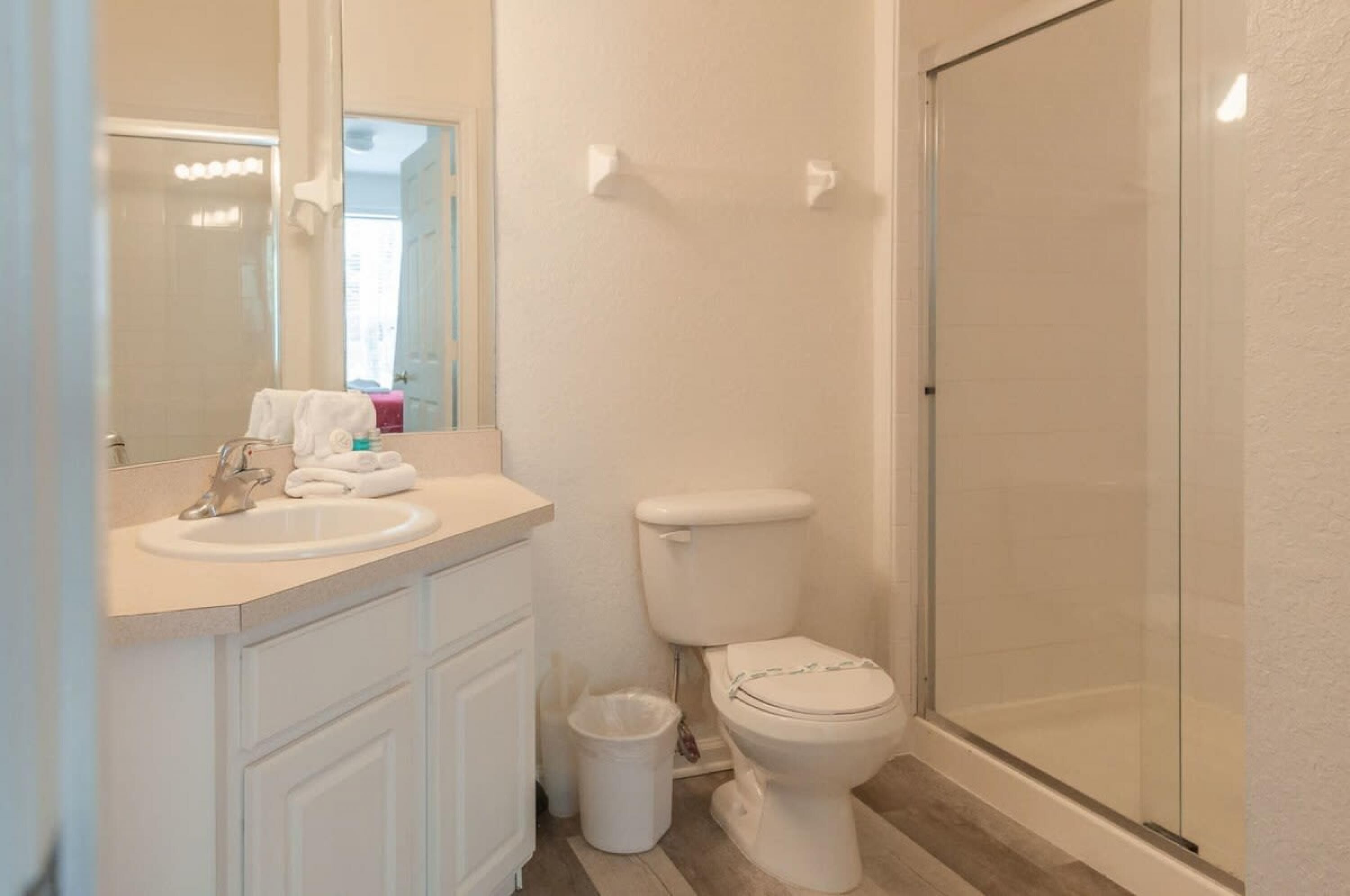 A bathroom with a sink, toilet, and glass shower enclosure.