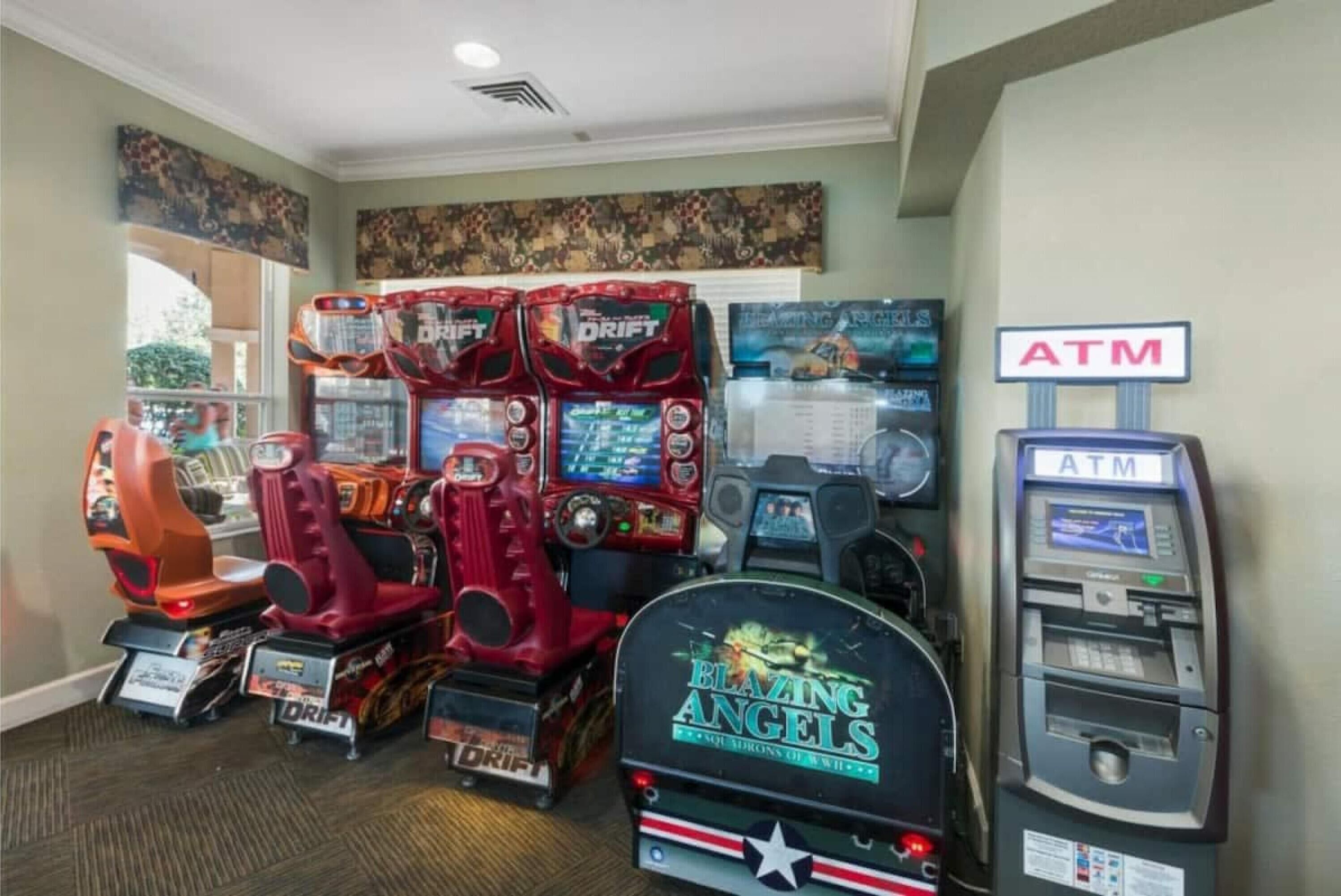 Ein Raum mit mehreren Spielautomaten, darunter die Spiele 'Blazing Angels' und 'Drift', sowie ein Geldautomat.