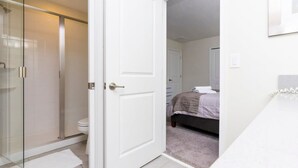 A bathroom with a glass shower enclosure, a white toilet, and a white sink. - 8912 Amazing 6BD Home (Davenport)