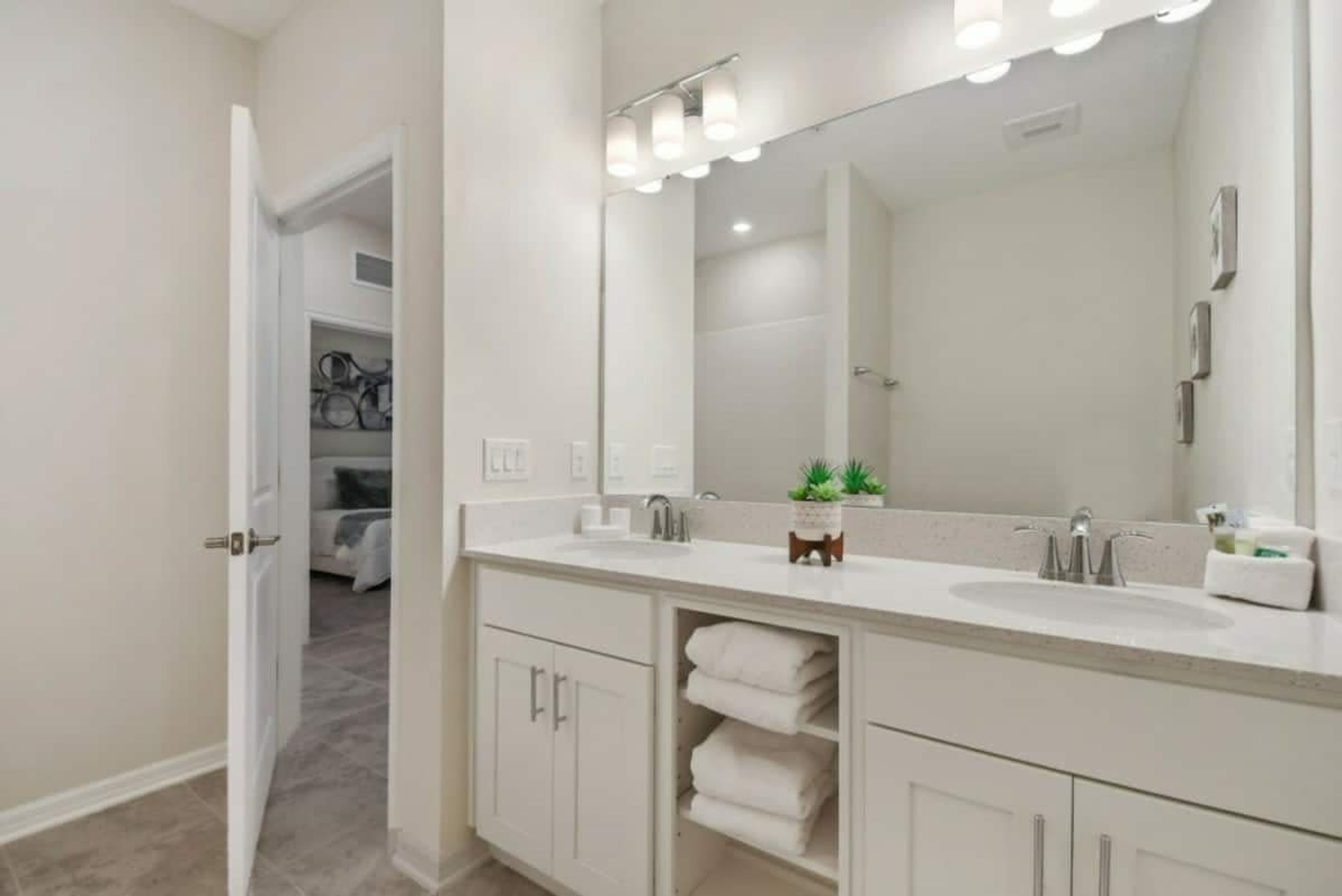 A modern bathroom with a large mirror, two sinks, and a towel rack.