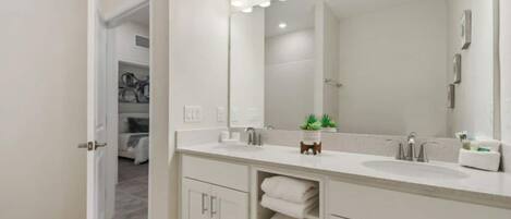 A modern bathroom with a large mirror, two sinks, and a towel rack.