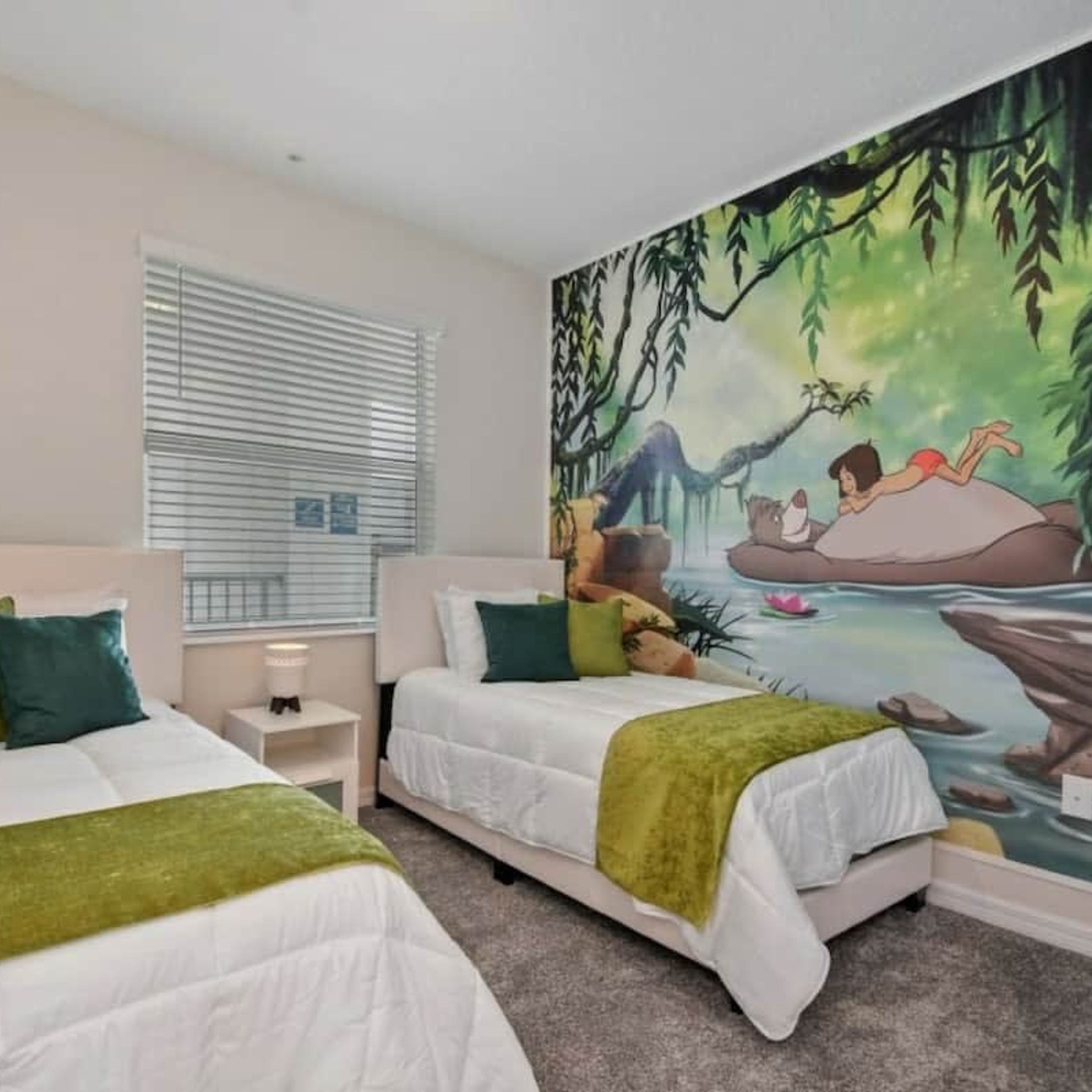 Quarto com duas camas, um grande mural de uma cena de selva e uma janela com persianas.