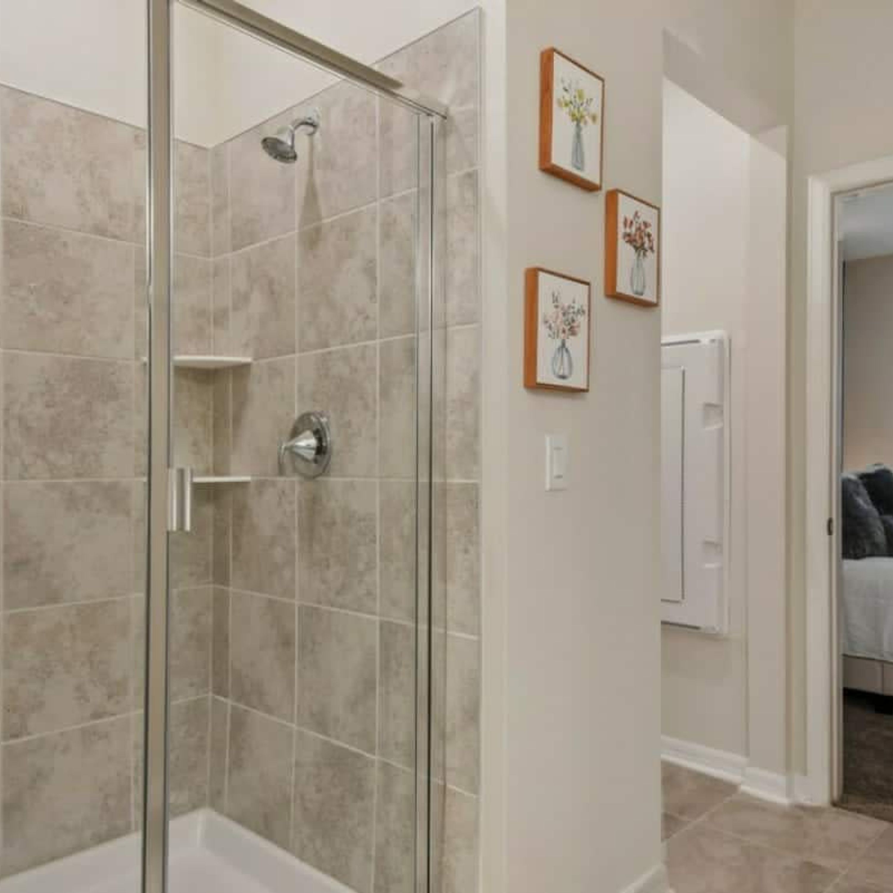 A bathroom with a glass-enclosed shower, beige tiles, and a white bathtub.