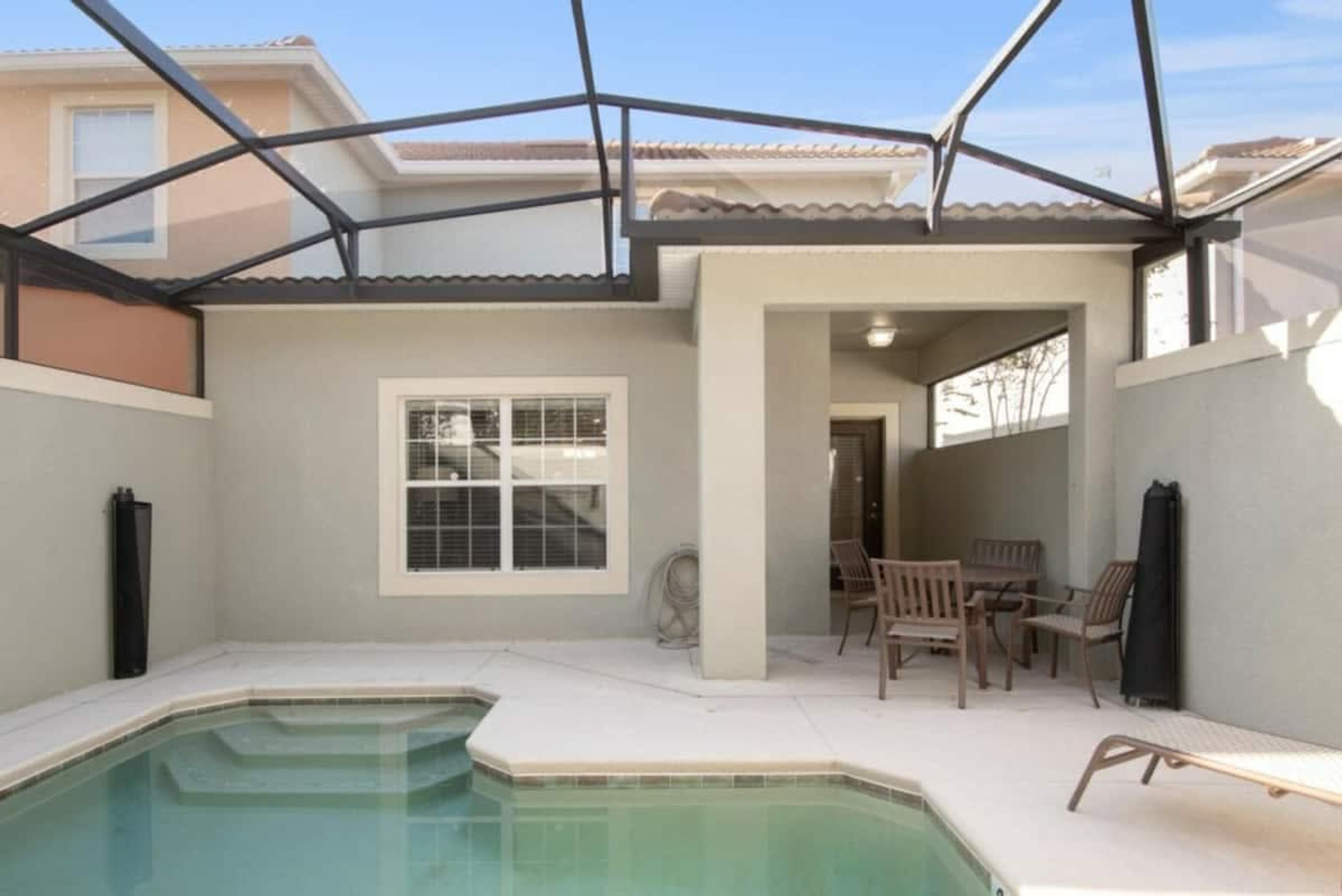 Une terrasse couverte avec une piscine, des sièges d’extérieur et une vue sur un immeuble d’habitation.