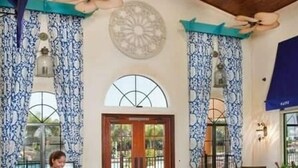 A reception area with a desk, chairs, and a large window with curtains. - 9004 Amazing 5BD With Pool (Kissimmee)