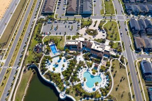 An aerial view of a resort with two large swimming pools, a central building, and a parking area. - 9012 Magical Home 5BD With Flowrider Surf Clubhouse (Kissimmee)