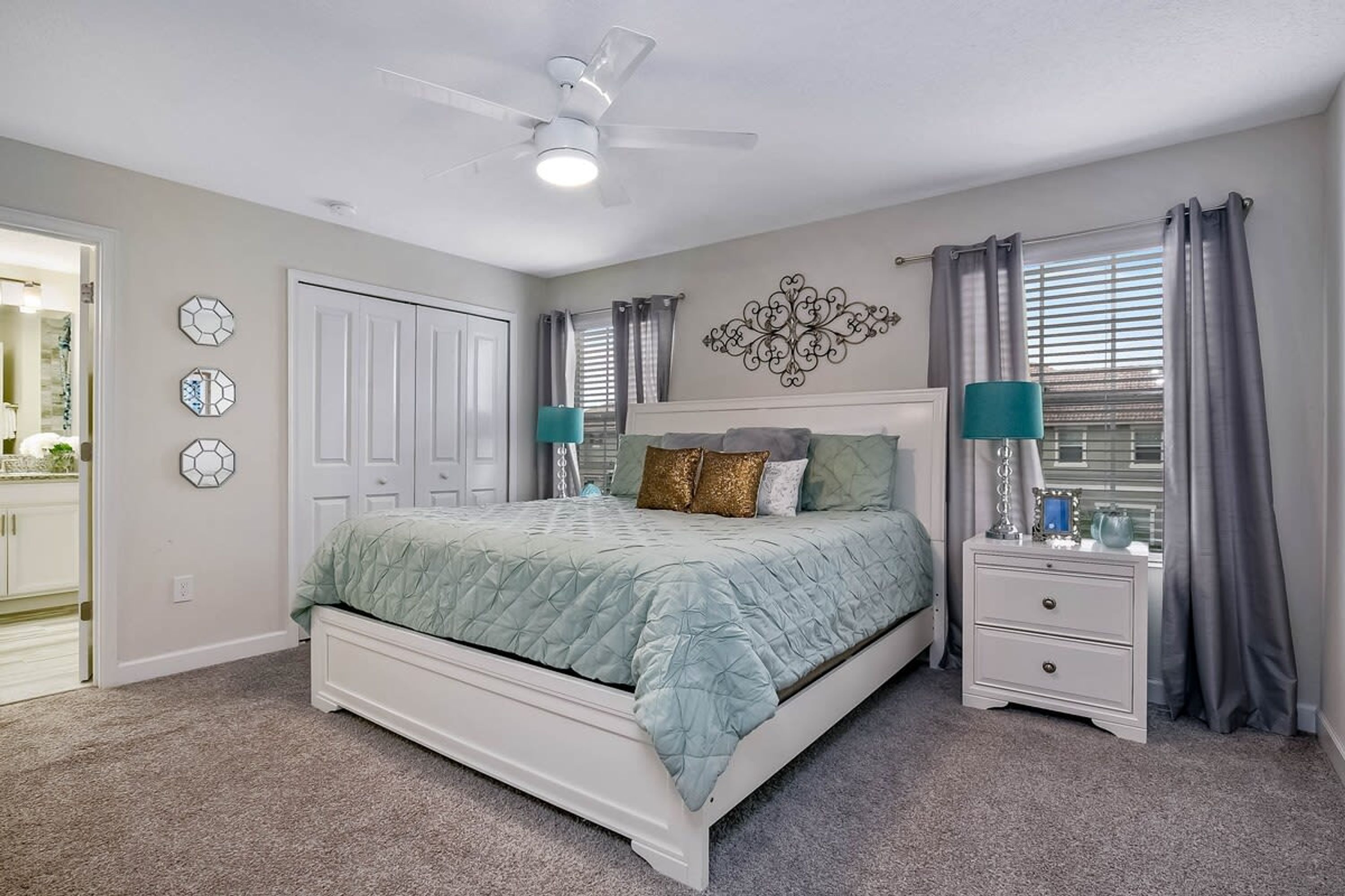A bedroom with a bed, nightstands, a ceiling fan, and a window with curtains.