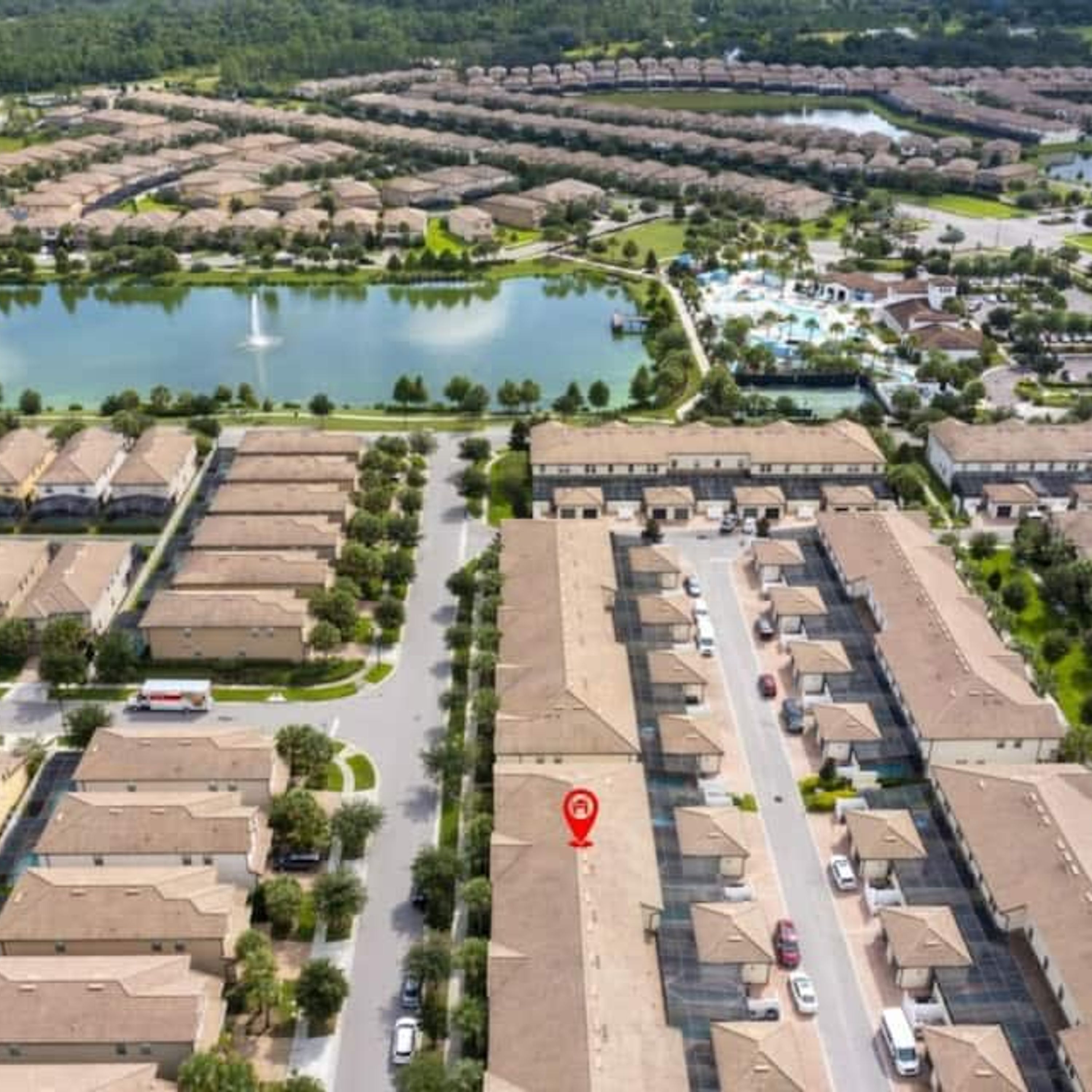A residential area with a central road, surrounded by houses and a lake.