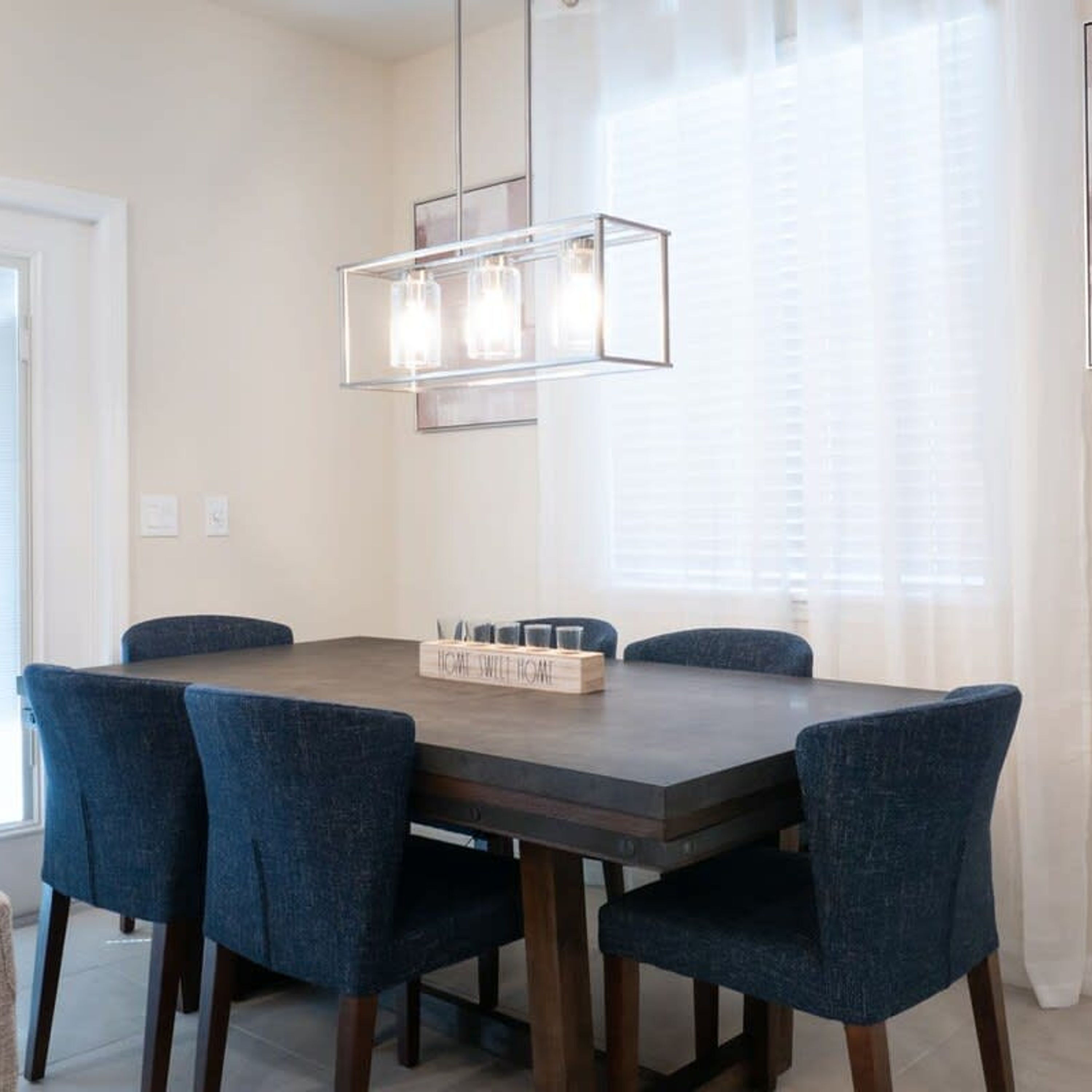 A dining area with a rectangular table, six chairs, and a pendant light fixture.