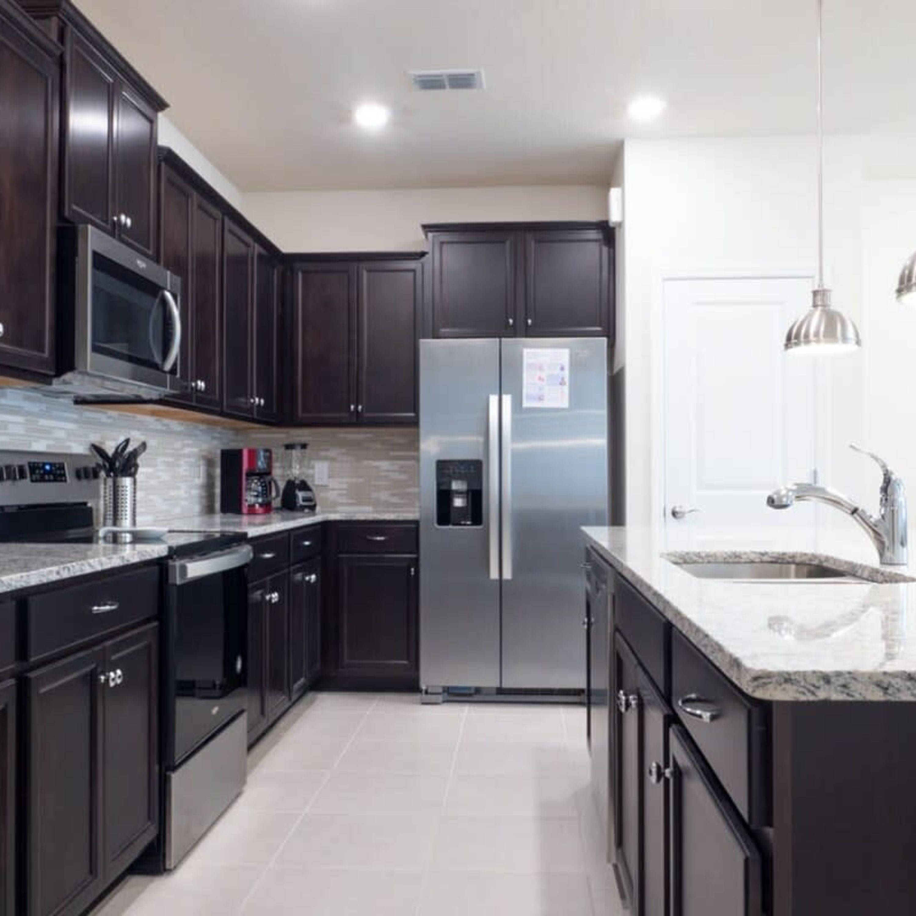 A modern kitchen with dark cabinetry, stainless steel appliances, and a granite countertop.