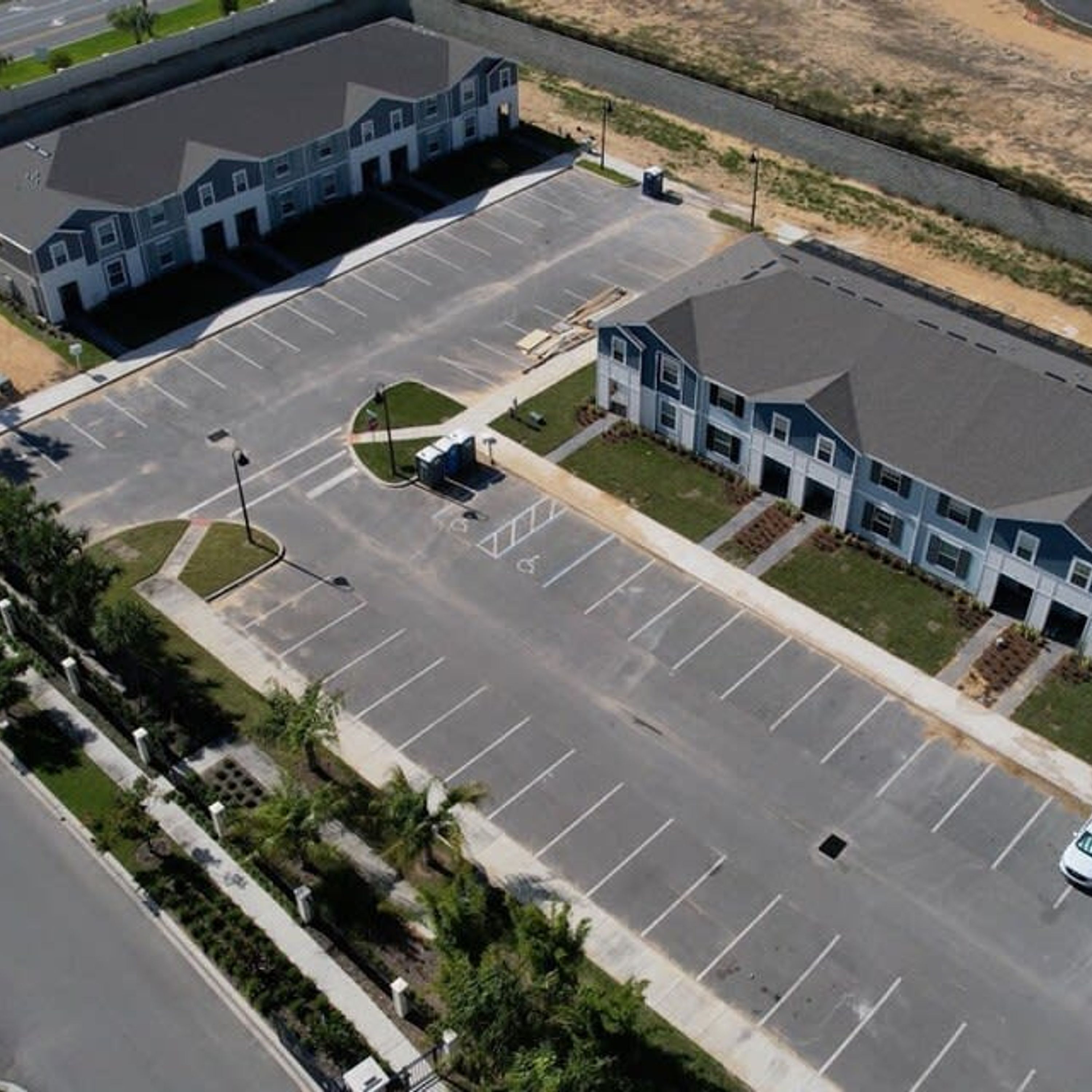 An aerial view of a parking lot with a building adjacent to it.