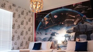 Un dormitori amb dos llits, un mural de tema Star Wars i una làmpada penjant.