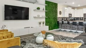 Ein modernes Wohnzimmer mit Flachbildfernseher, Sofa und Couchtisch.