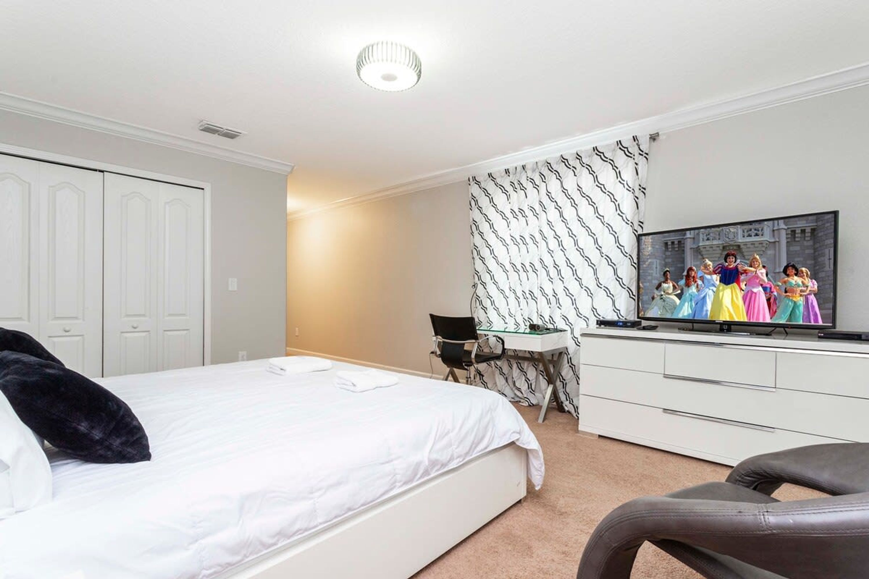 Quarto com cama, escrivaninha, televisão e armário.