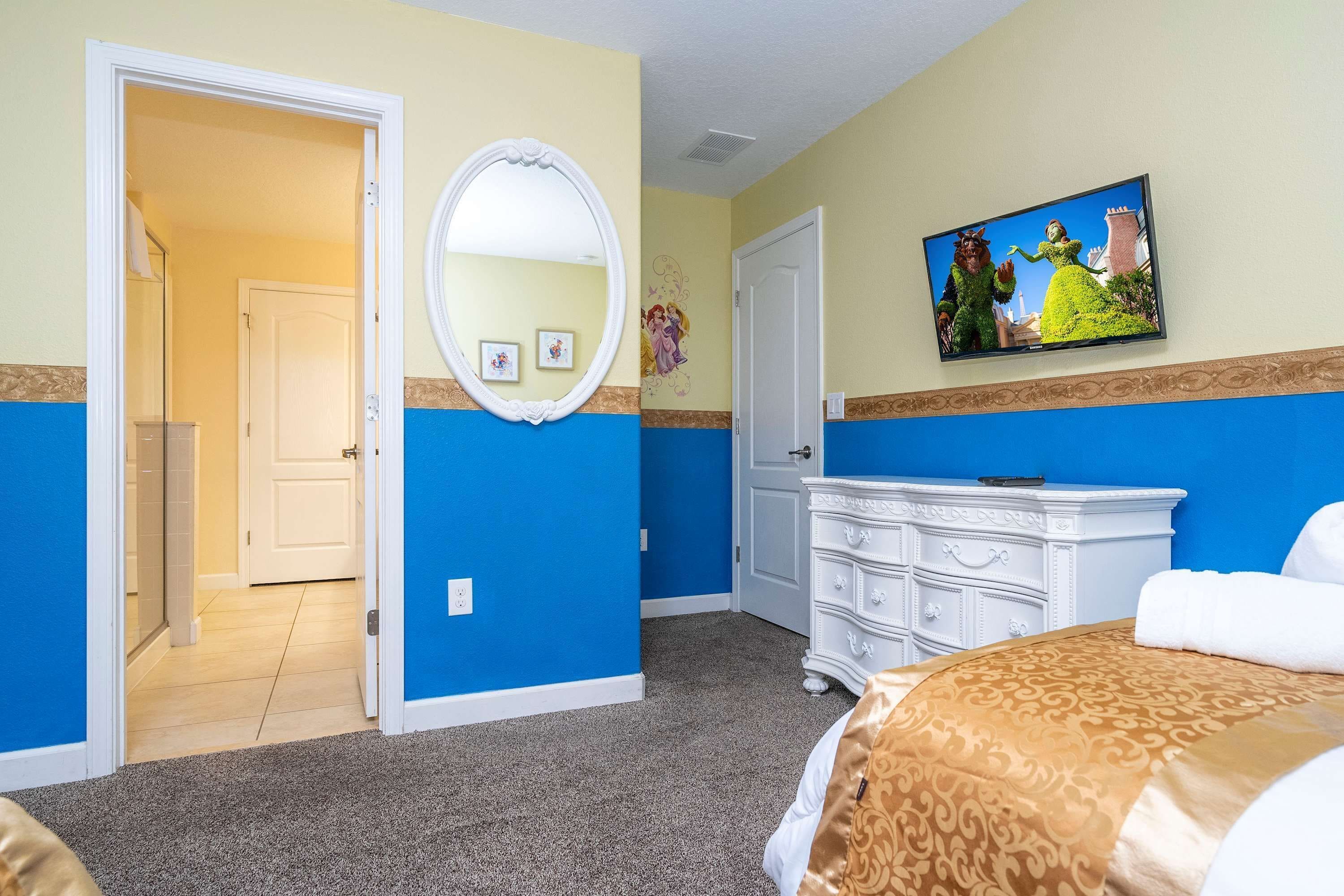 A hotel room with a bed, a dresser, a mirror, and a television on the wall.