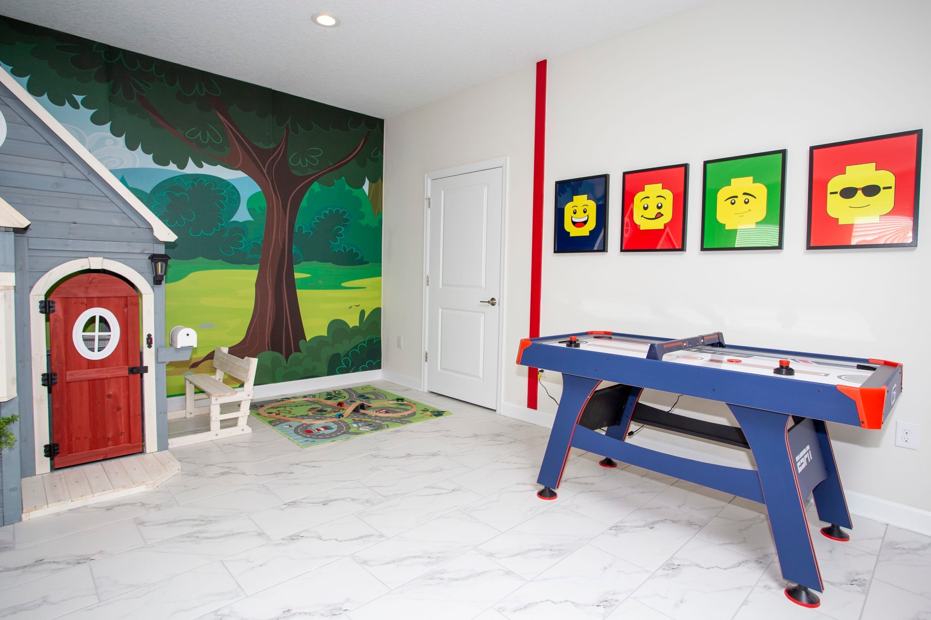 Una stanza con tavolo da biliardo, una porta rossa, un murale raffigurante un albero e quattro quadri appesi al muro.