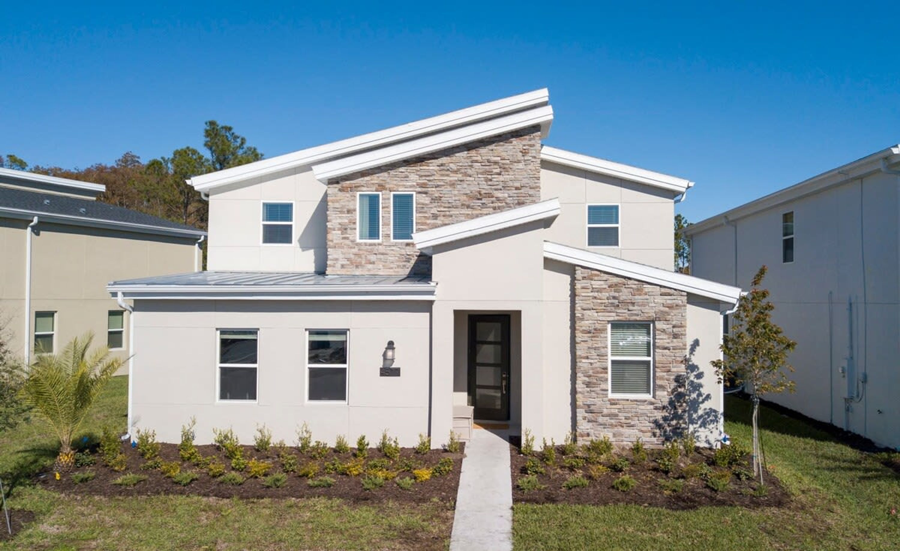 A modern two-story house with a stone facade and a flat roof.