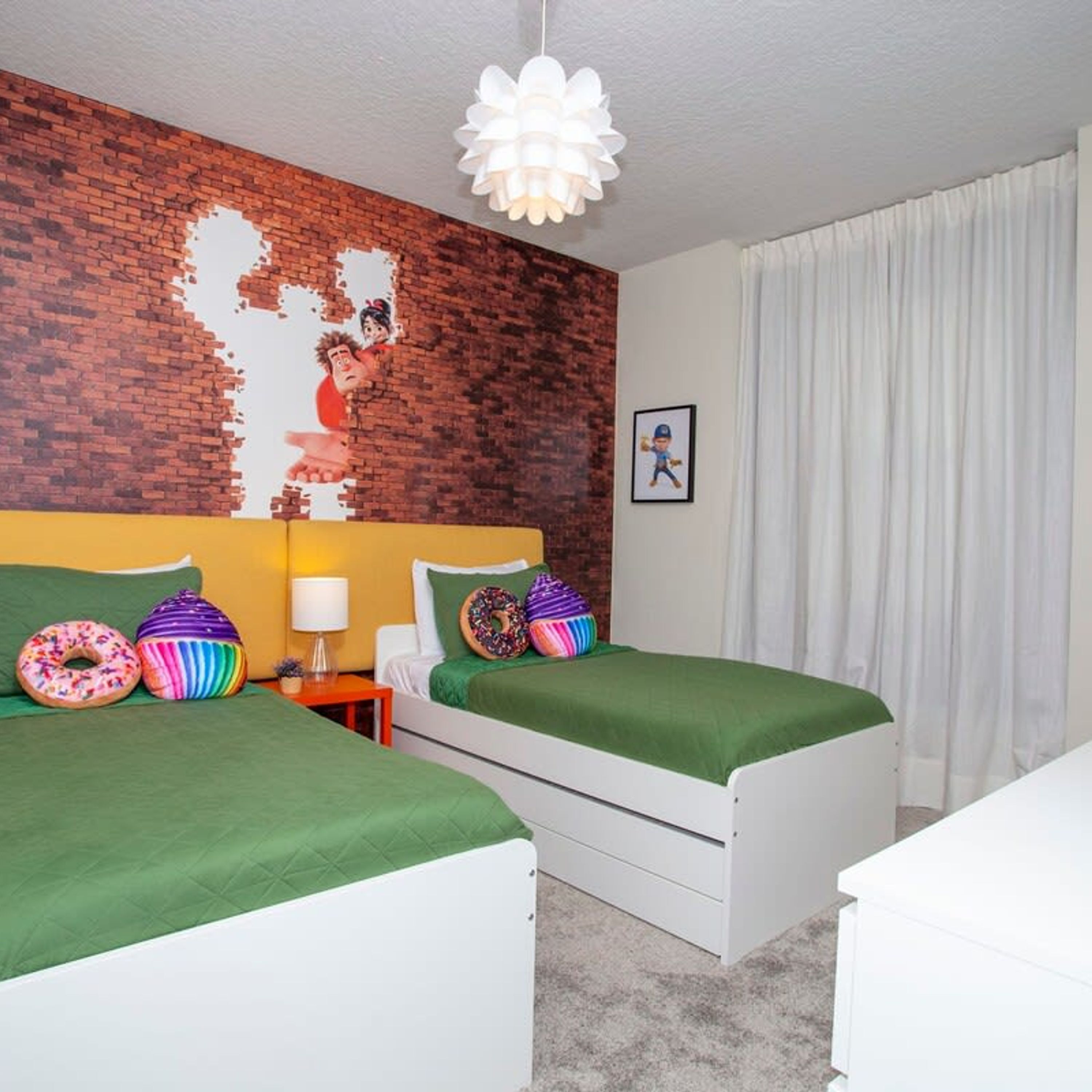 Une chambre avec deux lits, un mur en briques, un plafond blanc, une lampe blanche et un tableau accroché au mur.