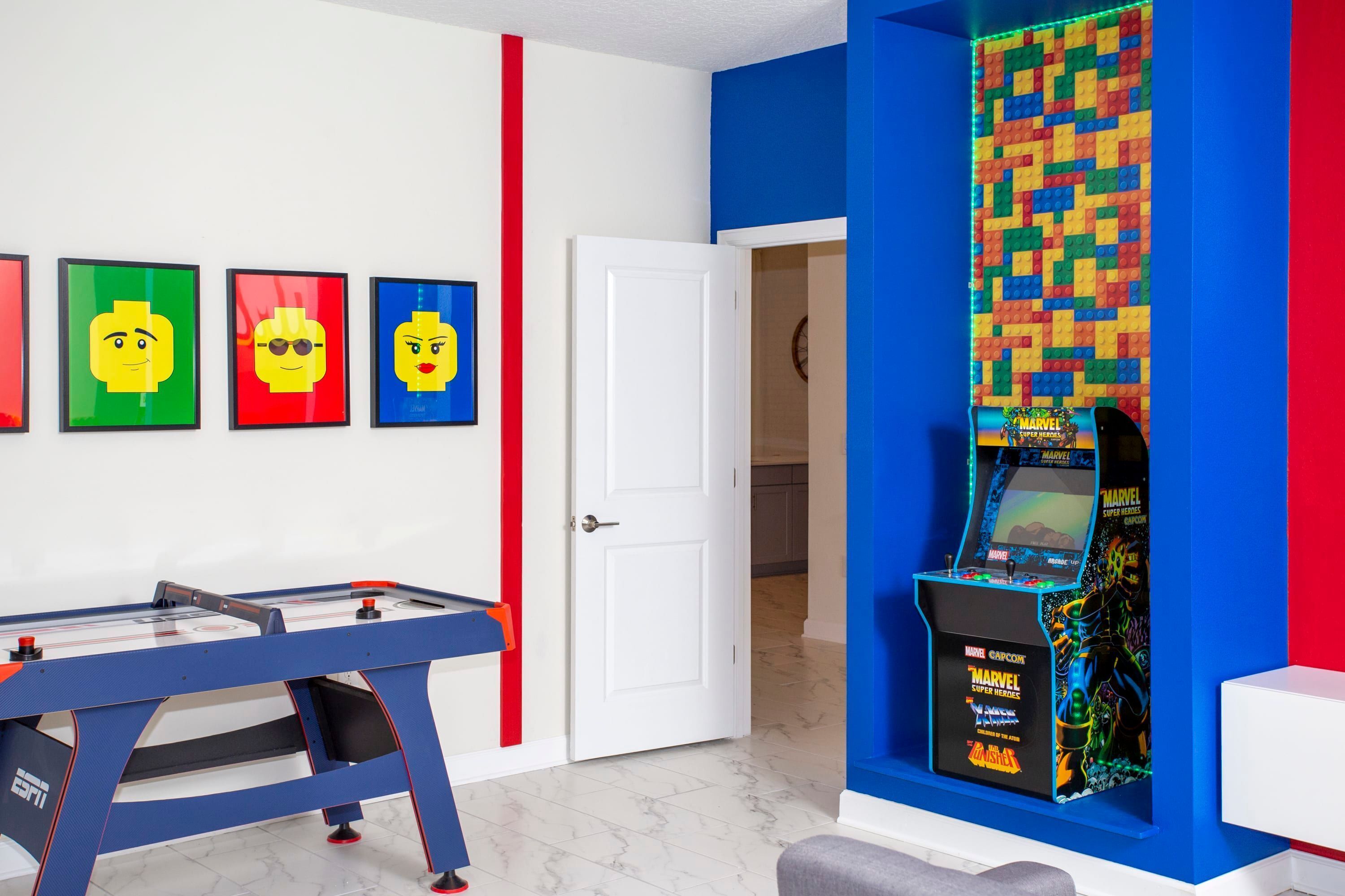 A room with a foosball table, a wall-mounted video game console, and framed artwork on the wall.
