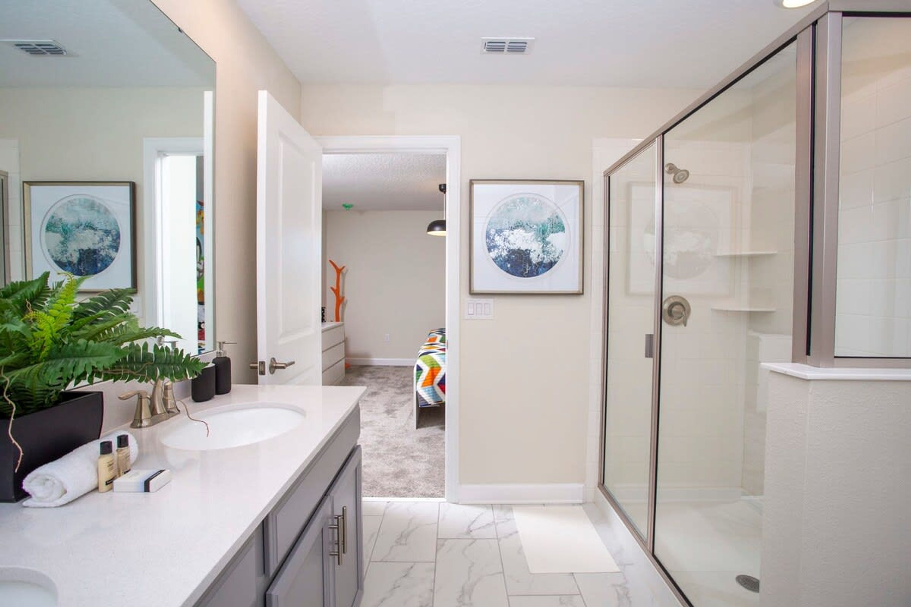 A modern bathroom with a glass shower enclosure, a large mirror, and a double sink vanity.
