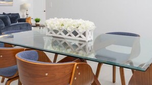 A modern dining area with a glass table, wooden chairs, and a white floral centerpiece. - 150 Stunning 4BD Perfect for Your Vacation (Davenport)