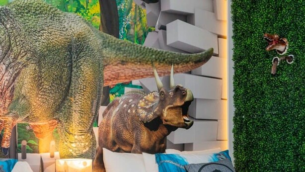 A bed with dinosaur-themed pillows and a wall with a green artificial grass backdrop. - 150 Stunning 4BD Perfect for Your Vacation (Davenport)